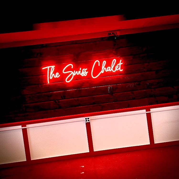 Neon sign that says The Swiss Chalet.