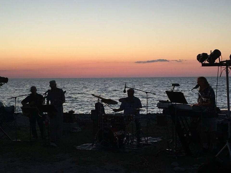 Band in front of a sunset by the lake.