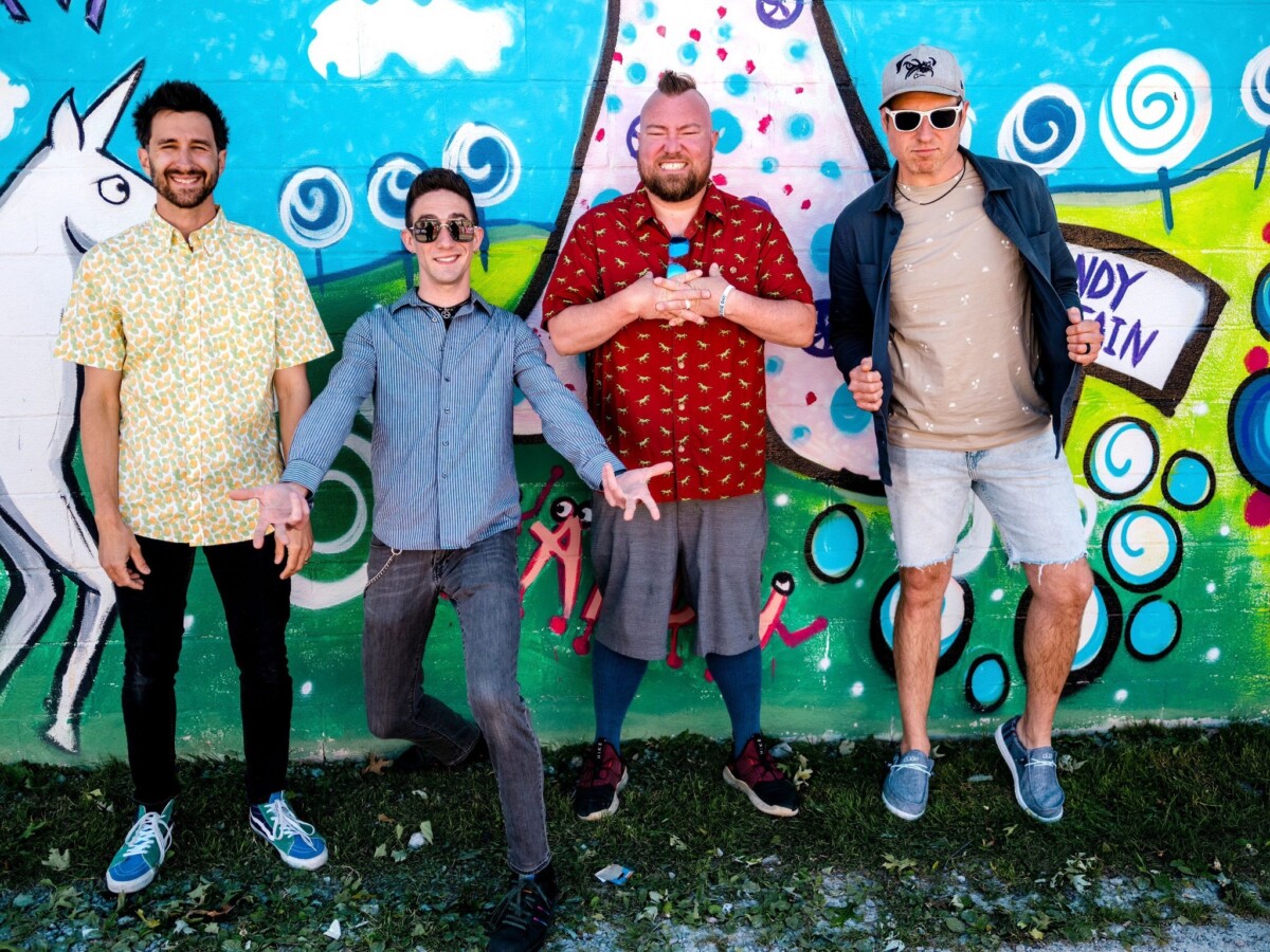 4 guys in front of colorful mural