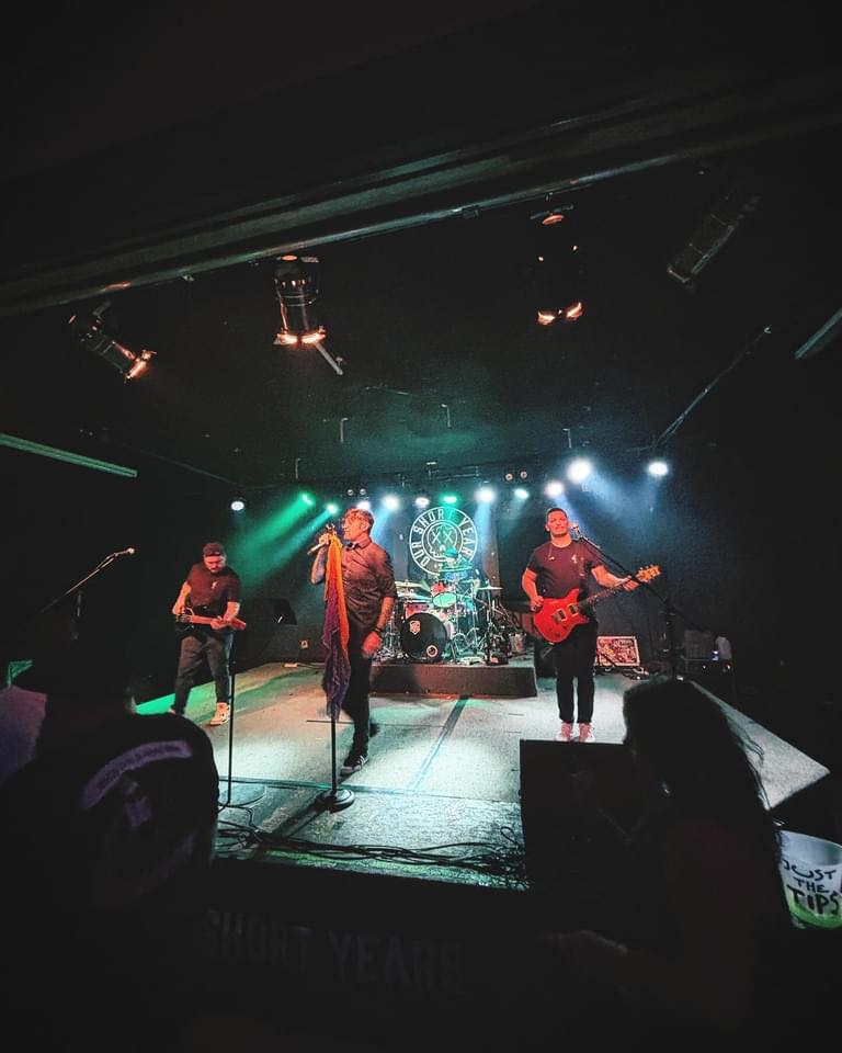 Band on stage with instruments and lights.