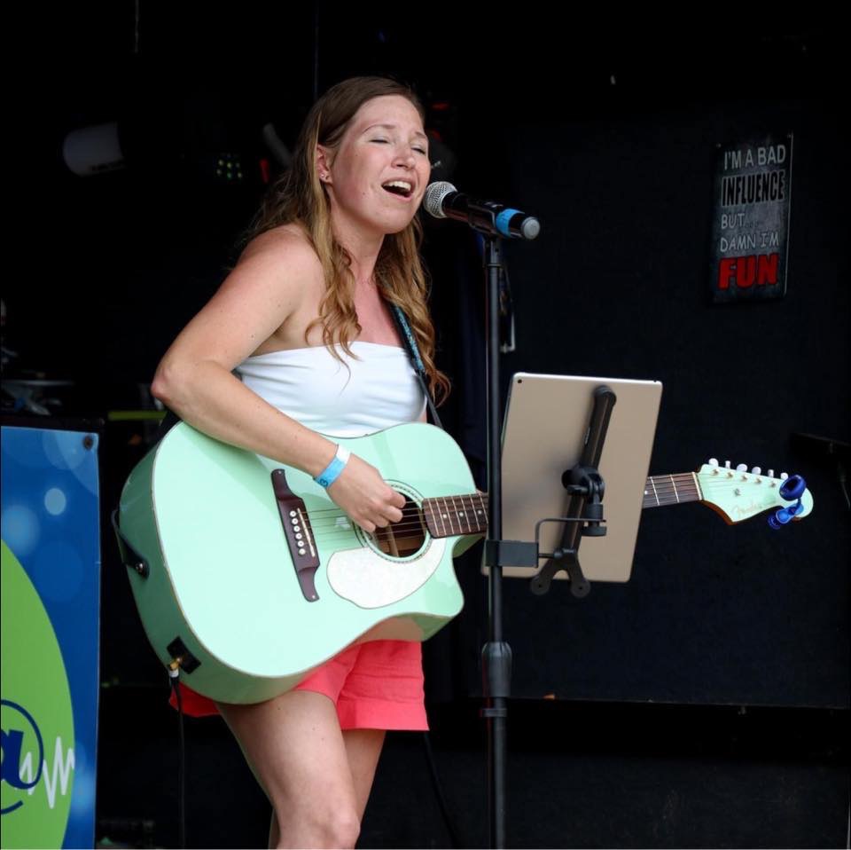 Female musician singing while playing guitar.